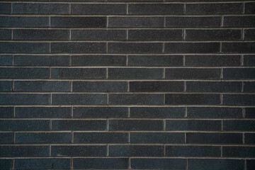 Dark Black Brick Wall Material Texture Background with repeating rectangular bricks of different...