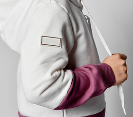 Close up side view of little child hands in sports suit on gray background.