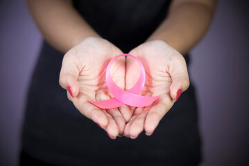 A woman has a pink ribbon attached to her palm for breast cancer awareness. Concept of health care and medicine