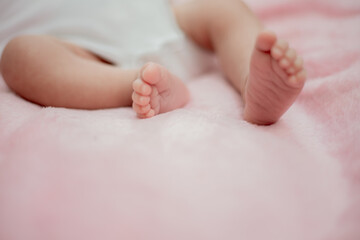 Obraz na płótnie Canvas baby feet in bed The little boy's feet are sleeping on the pink mattress