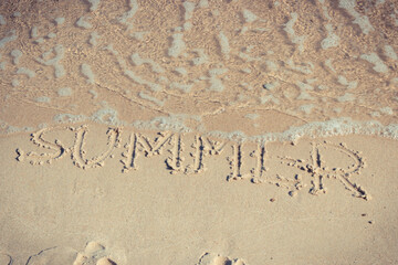 Inscription summer and sea wave on sand at beach. Vacation time