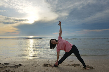 Fototapeta na wymiar healthy woman practicing yoga on the beach at sunrise