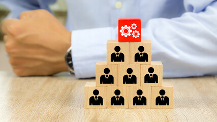 Cog with people icon on cube wooden toy blocks stacked in a pyramid shape concepts of human...
