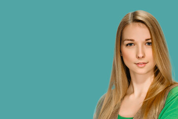 Attractive young girl with long blonde hair posing on turkish blue background