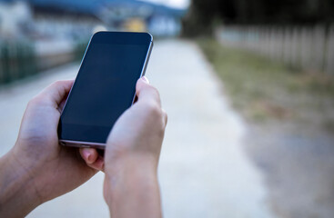 woman holding a smartphone with a blank black screen and empty space, technological ideas and text space.