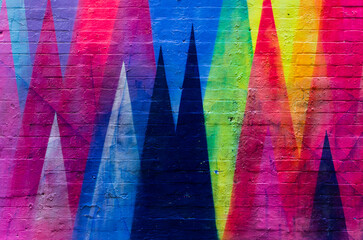 Fototapeta premium Brick wall painted in vibrant colors with geometric figures