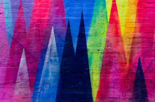 Brick wall painted in vibrant colors with geometric figures © IzzetNoyan