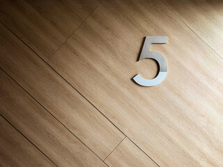 Number Five on parquet as a number concept background on wooden wall.