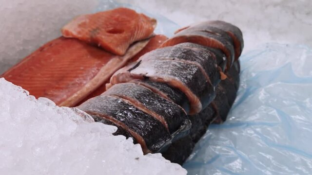There is a salmon in the shop window. The camera circled over the ice, where the red fish lies. Seafood on the counter