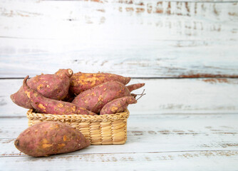 Sweet organic potatoes in basket on white table.