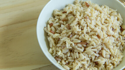 BROWN RICE in white bowl on wood table for health food content..