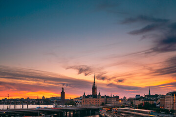 Naklejka premium Stockholm, Sweden. Scenic View Of Stockholm Skyline At Summer Evening. Famous Popular Destination Scenic Place Under Dramatic Sky In Sunset Lights. Riddarholm Church, Subway Railway