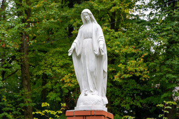 Posąg Maryi Panny na tle drzew
