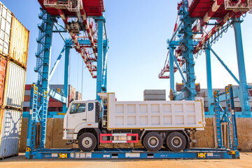 A truck stands on a flat track awaiting loading by STS cranes onto a ship at a container terminal