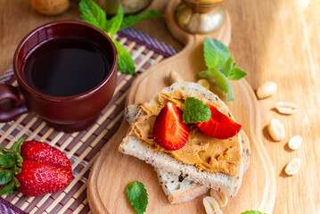 flat lay of peanut butter whole grain sandwich, top view of toast with strawberries on wooden table, healthy nutrition concept