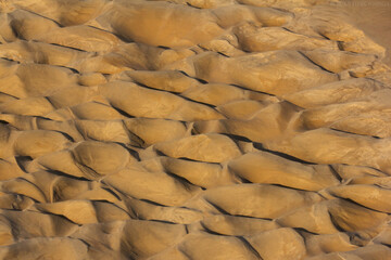 Fototapeta na wymiar Earth as an element, sand dunes interacting with water at the bottom of the river bed, taken after water drying, brown sand forming hills, abstract landscape 