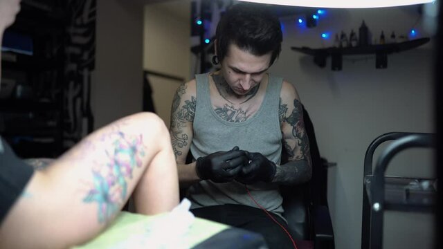 a professional tattoo artist collects the details of his tattoo machine in the salon in black styling gloves