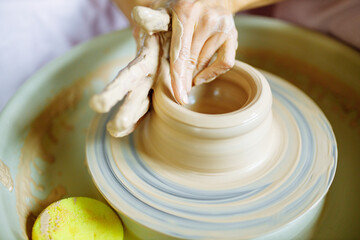 Potter hands sculpts a vase from clay on a Potter close up