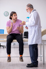 Fototapeta premium Young male patient visiting old male doctor