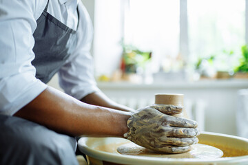 Portrait of positive latin hispanic brazilian man making ceramic pot on pottery wheel