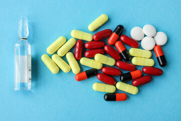 Multicolored pills, ampoule on a blue background