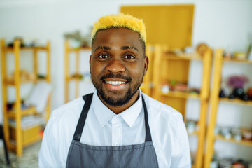 Portrait of positive latin hispanic brazilian man making ceramic pot on pottery wheel