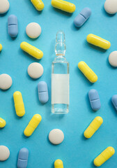 Various pills and ampoule on a blue background.