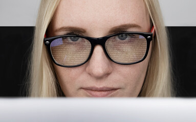 The programmer girl's glasses reflect moving lines of code. Programming, development of applications, sites and more. Software development concept