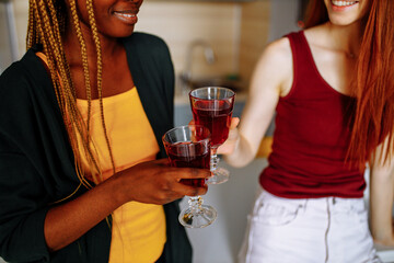 Interracial couple of girlfriends drinking wine in the room
