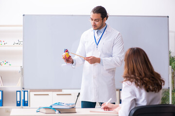 Young male doctor cardiologist and female student in the classro