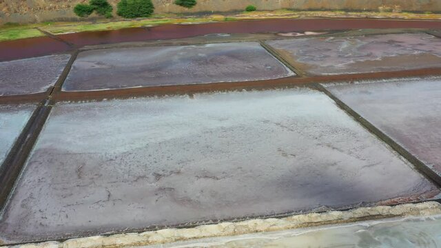 Aerial shot of the Pedra de Lume salt evaporation ponds, inside the crater of an extinct volcano. Camera flies and turns right focusing on the salt evaporation ponds.