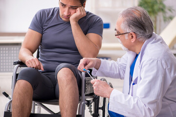 Young male patient in wheel-chair visiting old doctor