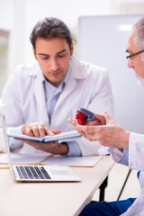 Experienced doctor cardiologist teaching young male assistant