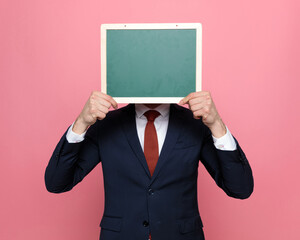 elegant businessman in suit covering face with blackboard