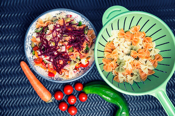 dish with mixed multicolored farfalle pasta salad and vegetable ingredients