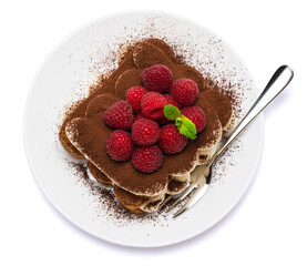 portion of Classic tiramisu dessert with raspberries on ceramic plate isolated on white background - clipping path