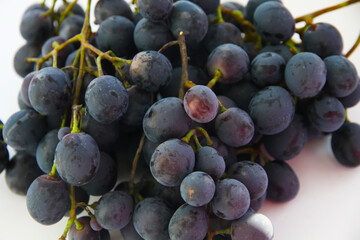 Black grapes, large fresh fruits with green leaves on a white background
