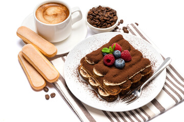 portion of Classic tiramisu dessert with raspberries, blueberries and cup of fresh hot espresso isolated on white background - clipping path