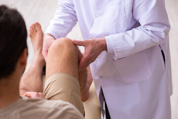Experienced doctor traumatologist examining young male patient