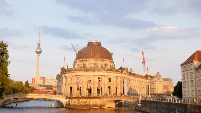 Berlin city center buildings architecture view with river Spree embankment, bridge train goes and TV tower needle in evening time on summer