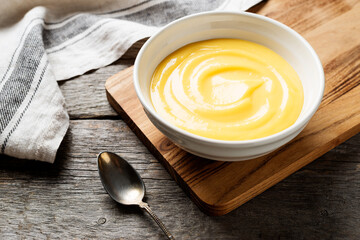 Homemade vanilla custard pudding or lemon curd in a white  bowl. - 376187383