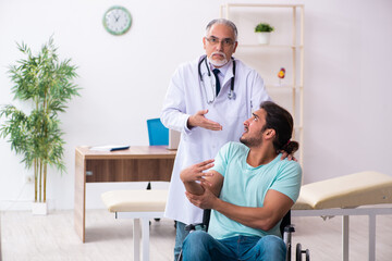 Experienced doctor and young male patient in wheel-chair