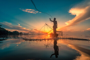 Nakorn Si Thammarat, Thailand-August 16, 2020 : Silhouette Fisherman Fishing Nets on the boat at...