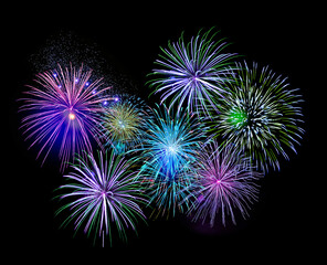 Explosive colorful green, blue and purple fireworks display in the night sky