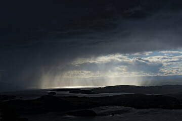 Dramatic storm clouds over a fjord as local rain shower closes in darkening the sky.
