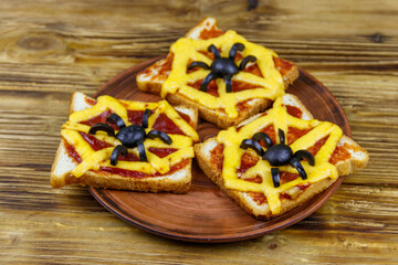 Funny sandwiches with spider and spider web for Halloween party on wooden table