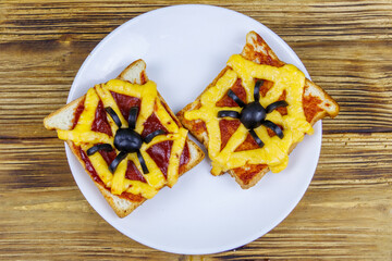 Funny sandwiches with spider and spider web for Halloween party on wooden table. Top view
