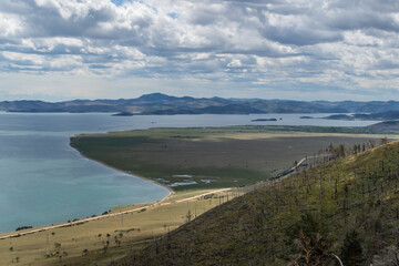 top view of the bay of lake Baikal with islands, peninsulas, mountains and hills with green trees in sun light
