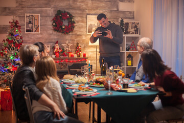 Smiling man taking group photos of his family at christmas celebration.