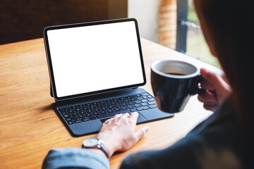 Mockup image of a woman using and touching on digital tablet touchpad with blank white desktop screen as a computer pc while drinking coffee
